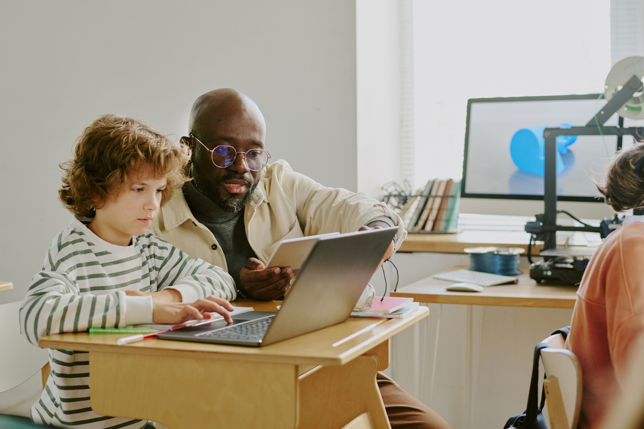 Teacher helping student at laptop